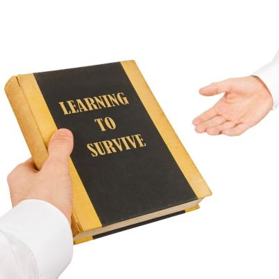Käsi ojentaa kirjaa toiselle kädelle. Kirjan kannessa lukee: Learning to Survive.