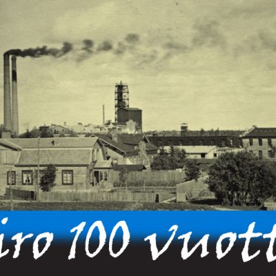 1920-luvun tehdasrakennuksia. Kaksi korkeaa savupiippua tupruttaa savua taivaalle.