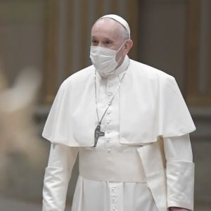 Påven Franciskus, med ett munskydd på ansiktet, med en julgran i förgrunden.