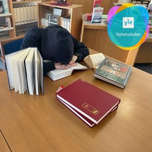 En elev böjd över böcker i ett bibliotek.