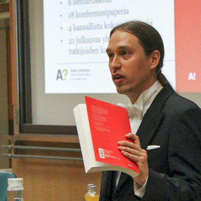 Taneli Riihonen puhuu kirja kädessään.