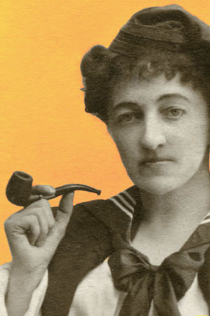 En kvinna,  Eugenie Grünberg, poserar på bilden med en pipa i handen. Bilden är från någongång 1890-1919.