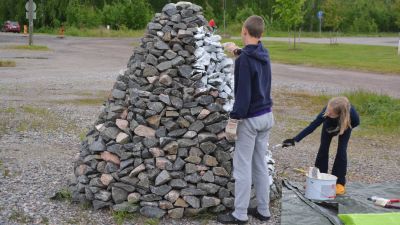 barn målar ett kummel av sten på västra åstranden i borgå