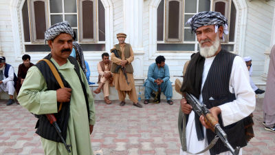 Två män med stormgevär står och vaktar krigsherren Muhammad Ismail Khans hus i Herat.