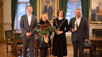 Prisutdelning med fyra personer i bild. Från vänster: Julius Håkans, Mari Håkans, borgmästaren Minna Arve och Joakim Håkans. 