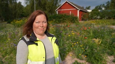 En kvinna står framför en blomsteräng.