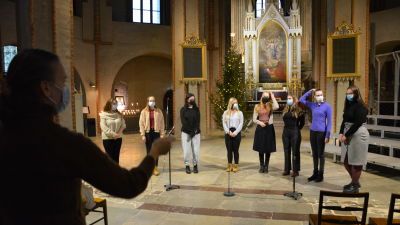 Åtta unga damer står framför altartavlan i Åbo Domkyrka och övar inför ett luciauppträdande. I bakgrunden syns en julgran.