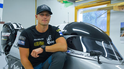Alexander Lindholm sitter på huk vid sin gråa formel 4 racerbåt.