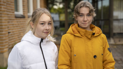 Två personer står framför Ekenäs gymnasium.