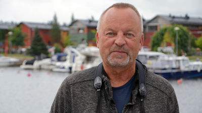 Man står med en kikare runt halsen vid Borgå å.