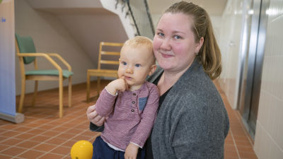 Anna Lindgren sitter med sin son på golvet. Hon tittar in i kameran.