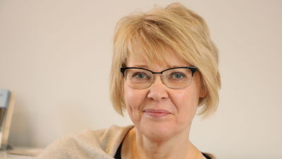 En kvinna med kort blont hår och glasögon.
