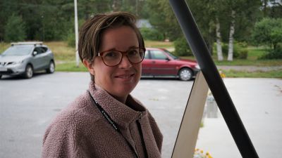 Kvinna med glasögon ler mot kameran.