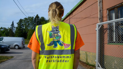 En kvinna iklädd reflexväst fotograferad bakifrån.
