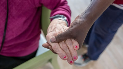 En skötare håller en pensionär om handen.