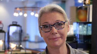En kvinna med glasögon står bakom disken på en restaurang.