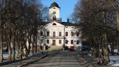 En byggnad i vitt och fotgängare som går på en trottoar.