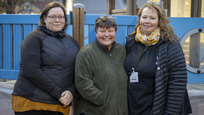 Tre kvinnor med ytterkläder står ute, utanför ett daghem (som inte syns)