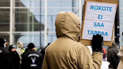 En demonstrant håller upp en skylt där det står "Ett vaccin får inte döda" under en coronademonstration i Helsingfors i mars 2021.