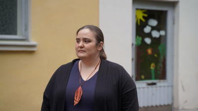 en medlemålderskvinna i mörkt hår som tittar över skolgården
