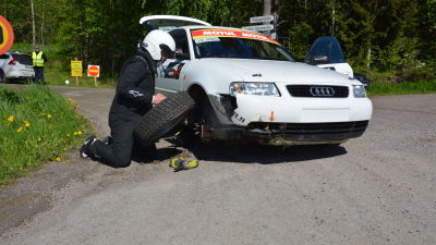 En man byter däck på en bil.