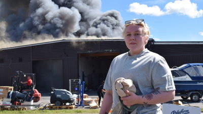 En kvinna i grå t-skjorta står framför varuhuset Hurrikaani som brinner i Kimitoön.