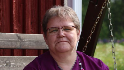En kvinna med glasögon sitter i en gunga.