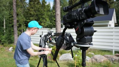 Ung man i keps och t-skjorta står vid en videokamera.