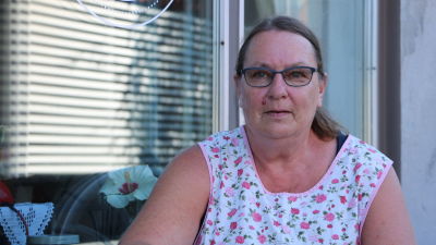 En kvinna med glasögon sitter framför ett fönster.