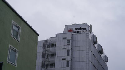 Bodens kommunhus med texten Bodens kommun. I bakgrunden regnmoln.