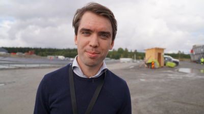Anders Thor tittar in i kameran. I bakgrunden fabriksområdet.