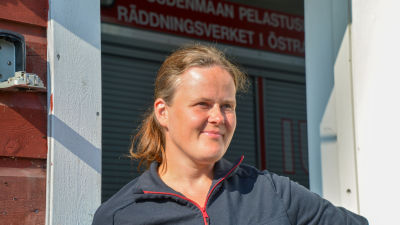 Johanna Nyholm står i solen vid dörröppningen till Wessö FBK:s brandstation.