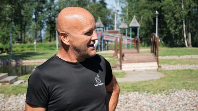 Man i svart t-skjorta står på ett campingområde.