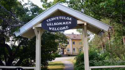 En skylt med texten "välkommen" på tre olika språk framför Sagalunds byggnad.