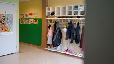 en tambur i en skola. I knaggen hänger jackor och väggarna är prydna av färgglada målningar gjorda av skolbarnen.