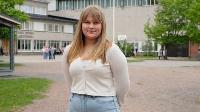 en gymnasiestuderande, ung tjej, i långt blont hår och vit tröjja.