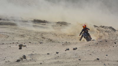 En motocrossförare åker på sand.