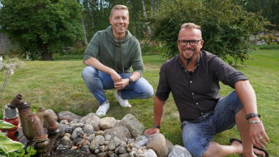 Två män som sitter i en trädgård bredvid en fontän som är byggd av ett gammalt stanklås.