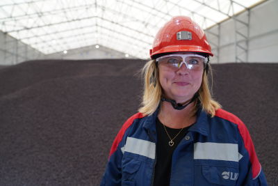 Monika Sammelin tittar in i kameran framför en hög av pellets.