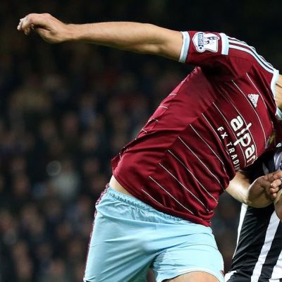 West Hamin James Tomkins hyppää palloon.