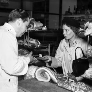 Kvinna köper kött med en ransoneringskupong i butik.