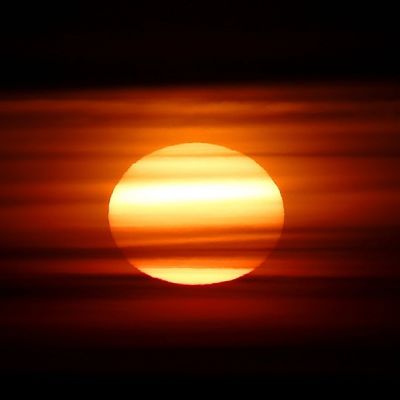Aurinko punertavien pilvien takana