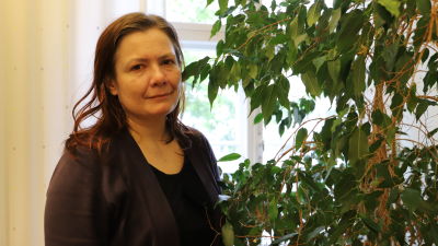 Kristina Friman står bredvid en krukväxt.