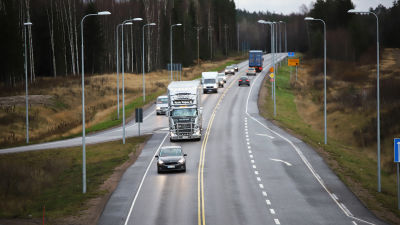 Personbilar och långtradare på landsväg.
