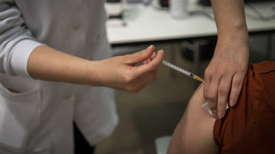 En skötare ger vaccin till en sittande person.