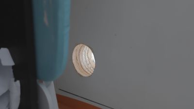 Ett hål som borrats i en balkongdörr, som fungerar som tillfällig ventilation. Hålets diameter är ungefär lika stort som en stor apelsin.
