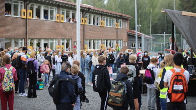 Meri-Porin koululaisia seisoskelee koulun pihalla lavan edessä. Kaksi pikkutyttöä julistaa koulurauhan