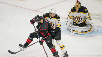 Sebastian Aho försöker styra en puck på Tuukka Rasks mål.