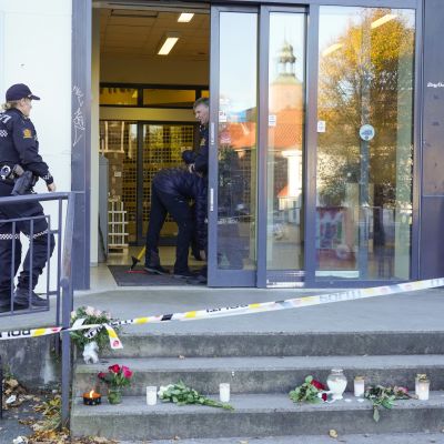 Poliisi jatkoi Kongsbergissa perjantaina kaupan tutkimista, jossa hyökkäys tapahtui. Kaupan edustalle on tuotu kukkia ja kynttilöitä.