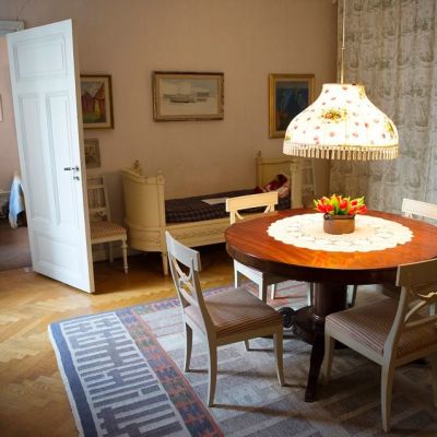 Näkymä asuntoon. Etualalla pöytä ja tuoleja. Taustalla sänky ja ovi toiseen huoneeseen.